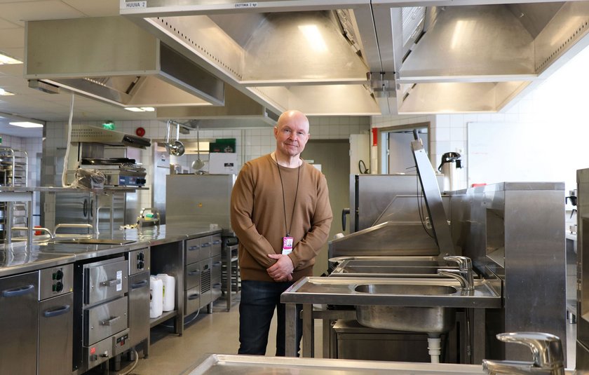 Tapio is standing in the middle of kitchen, where the students learn to cook.